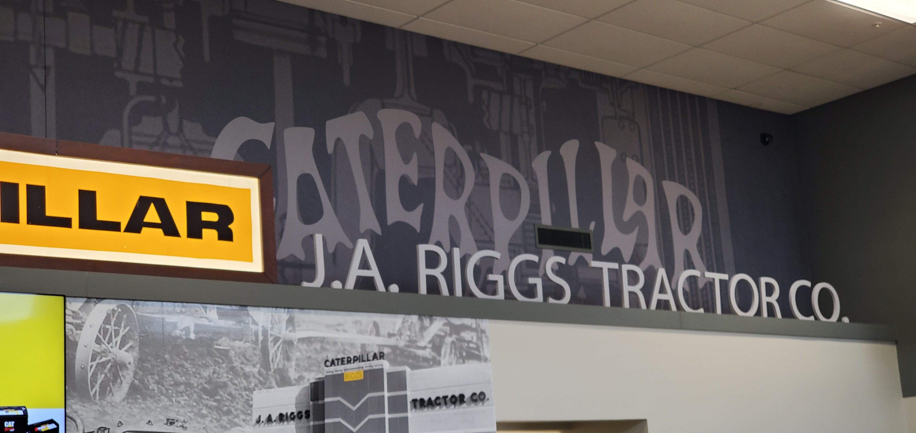Vintage Caterpillar wall covering with channel letters and a logo in an indoor setting