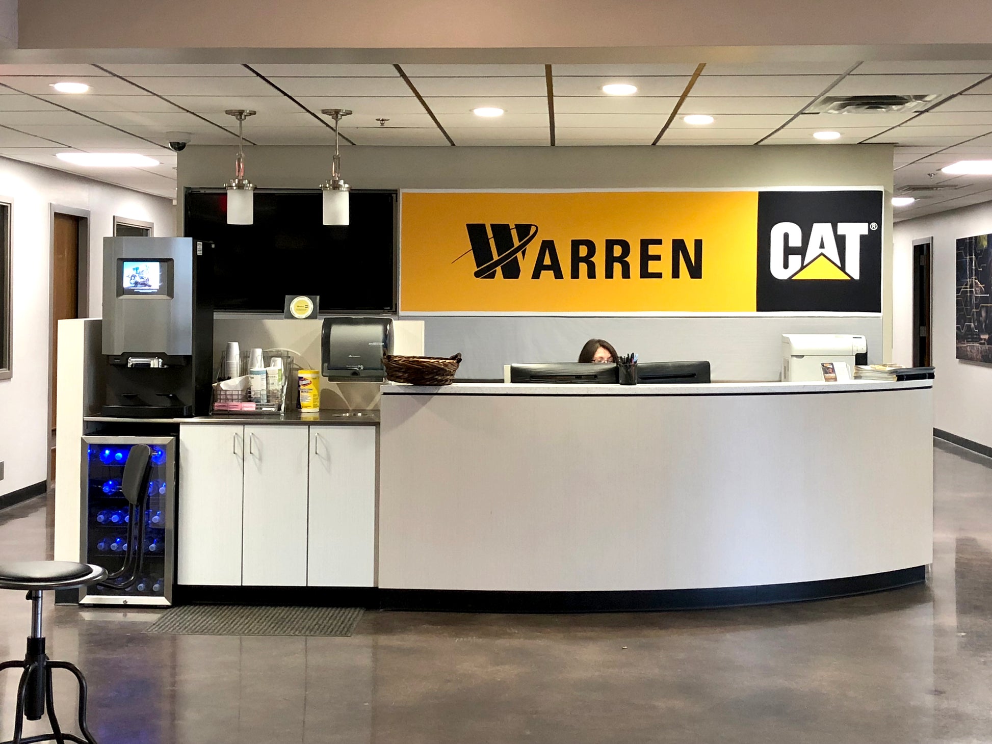 A reception desk with a large display panel featuring a yellow and black design, part of a signboard system.