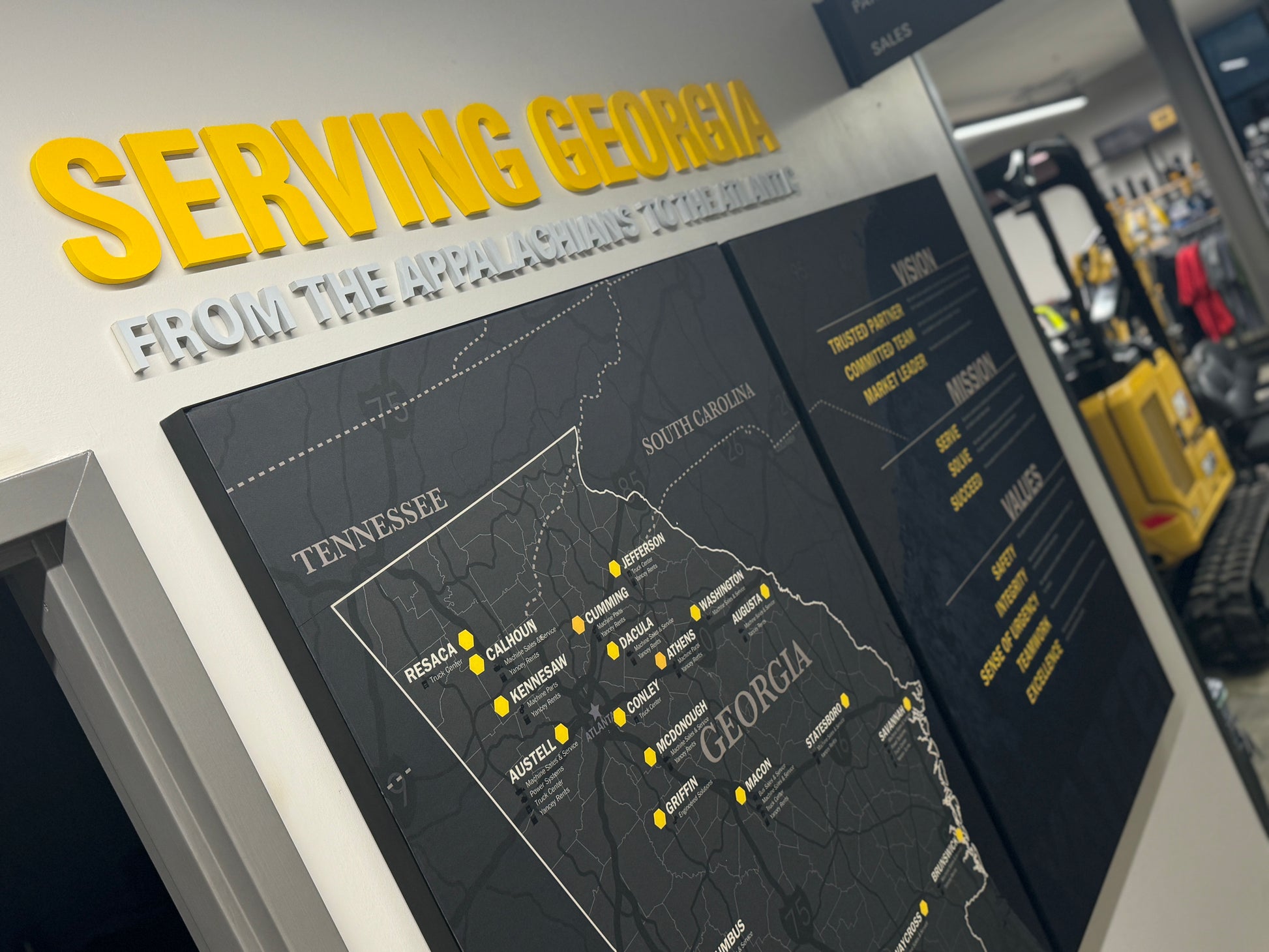 Territory Map for Caterpillar Dealer Showroom on a wall with 'Serving Georgia' text above it, in an indoor setting.