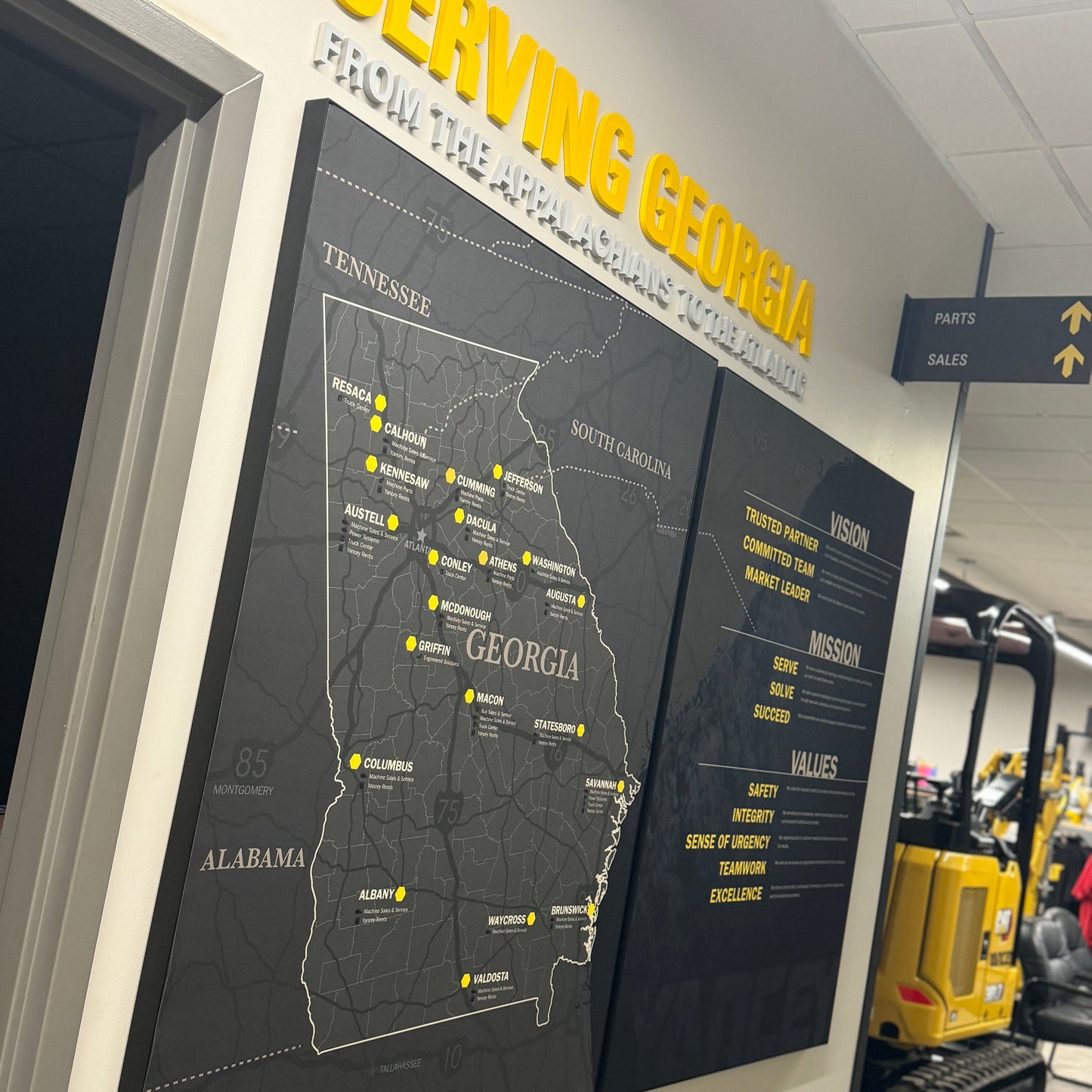 Territory Map for Caterpillar Dealer Showroom on a wall with 'Serving Georgia' text above it, in an indoor setting.