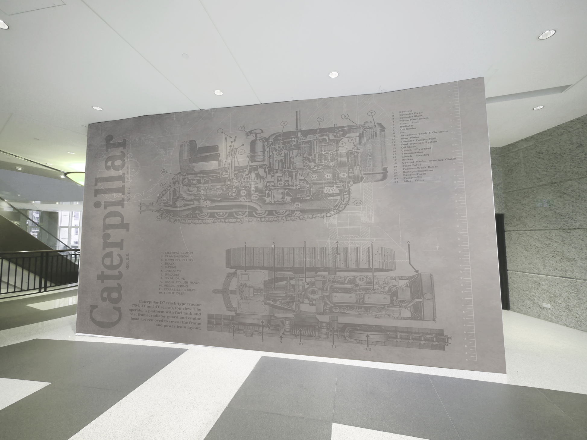 Large Caterpillar logo and machinery illustration wall covering in a modern indoor setting.