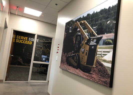 A large format product image panel featuring an image of construction equipment, displayed in an indoor setting, likely a showroom or office.